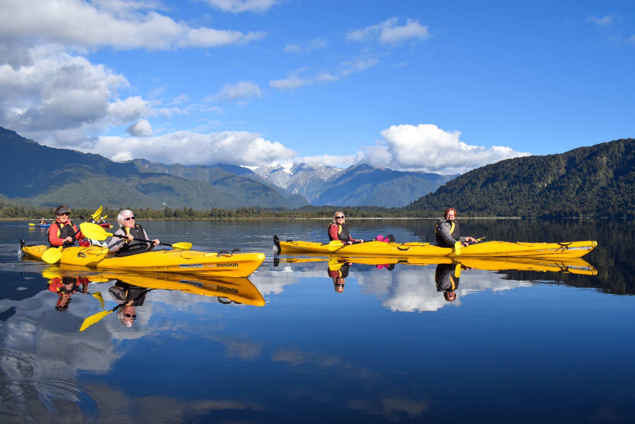Women in two person kayaks on the river in Franz Josef, New Zealand
